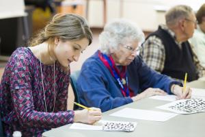 student working along side two older adults
