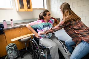 Two students are practicing transfers from a wheelchair.
