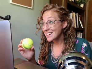 professor holding a tennis ball in front of a laptop