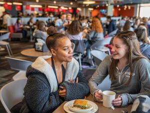 Two students in crowded Campus Center dining hall.