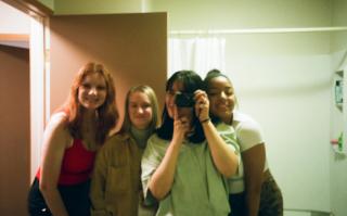 Anissa is posed in a group photo with three others in front of camera.