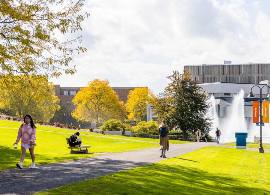 students walking across the quad with the fountains in the background