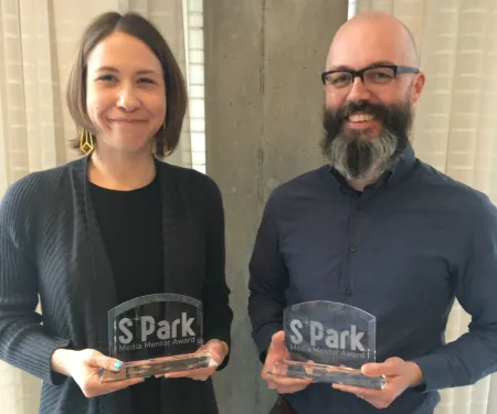 A man and a woman holding glass awards