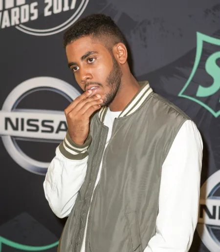 A man standing in front of a dark backdrop with logos