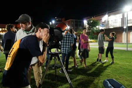 A young person looking through a telescope