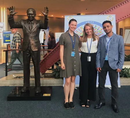 three students next to statue in hotel lobby