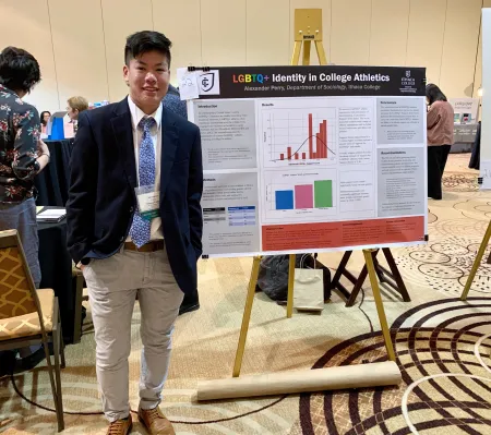 Person standing next to display reading LGBTQ identity in College Athletics