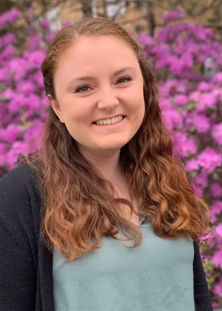 This is a photo of Abby Preston. Abby is wearing a light green shirt with a black sweater. Abby has long brown hair.