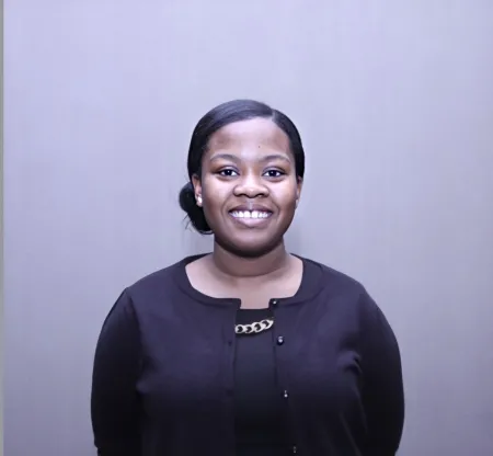 This is a photo of Christine King. Christine is wearing a dark long sleeve shirt. Christine's hair is in a bun and is smiling.