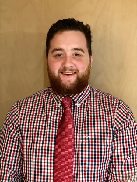 This is a photo of Cody Wamsley. Cody is wearing a red and blue checked shirt with a red tie.