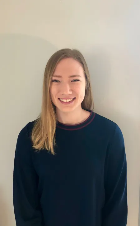 This is a photo of KellyAnne O'Reilly. KellyAnne is wearing a long sleeve dark blue shirt and has long blonde hair over the shoulder.