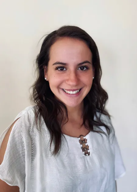 This is a photo of Marissa Holske. Marissa is wearing a white shit with a gold necklace.