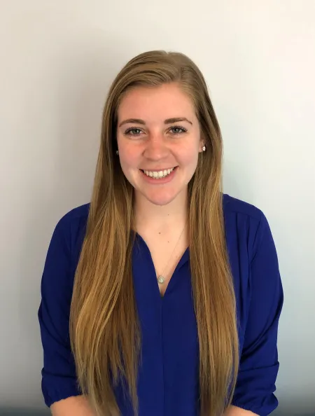 This is a photo of Rebecca DiSerio. Rebecca is wearing a long sleeve blue shirt with long hair over the shoulder.