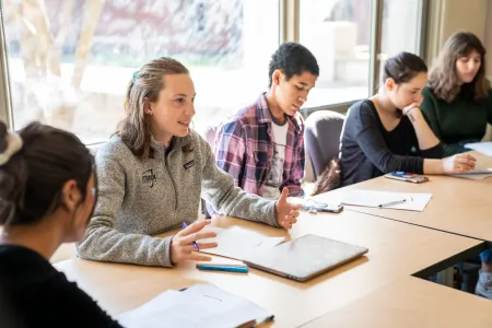 Students sitting around tables discussing topics in class.
