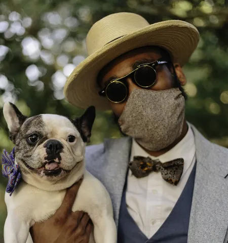 man wearing a mask, holding a dog