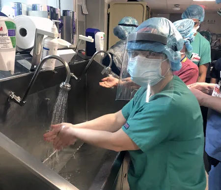 woman in PPE washing hands