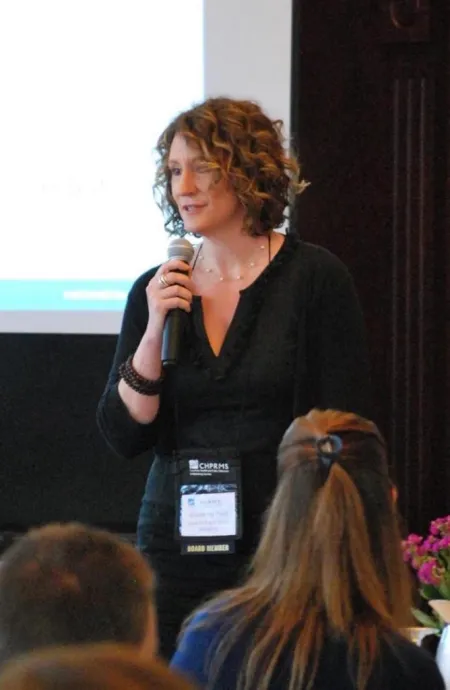 Woman holding microphone speaking to a group