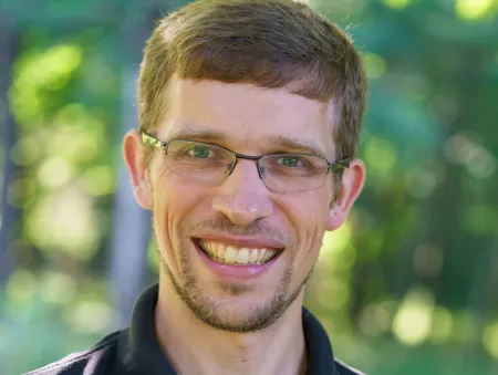 Headshot of a man in glasses smiling