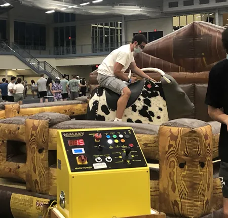 A student riding a mechanical bull.