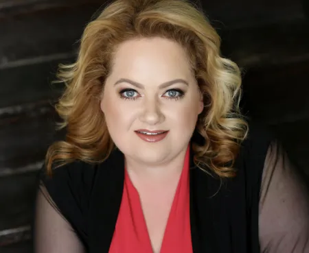 Headshot photo of person smiling in front of dark background