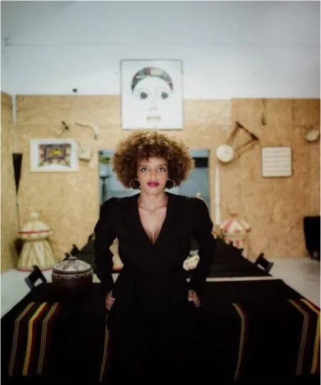 Image of woman wearing black dress with cork board background