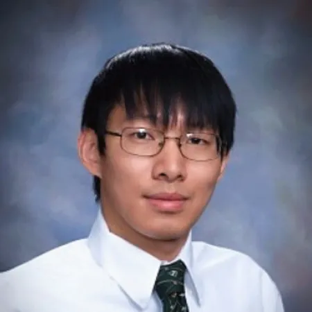 Austin is looking at the camera. He is wearing a white button down shirt and green tie.