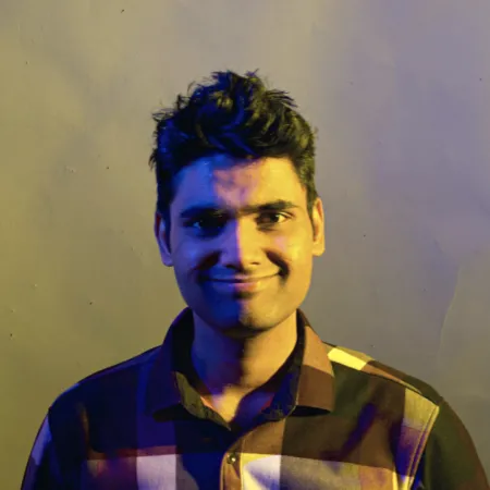 Vedant is smiling at the camera wearing a checked button up shirt.