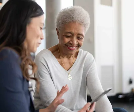 younger women of color showing an older woman of color something on a smart device
