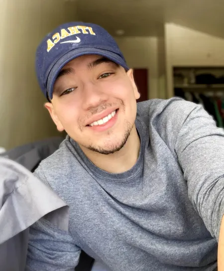 Christian is posing for a selfie. He is wearing a grey long sleeve shirt and blue Ithaca hat.