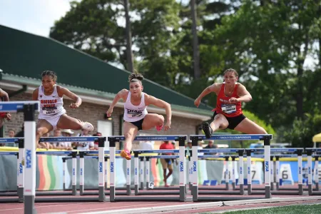 Student-athlete jumping over hurdles.