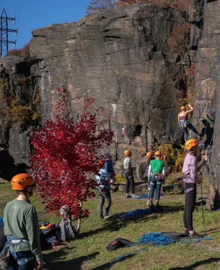 a group of students prepare to climb a rock wall