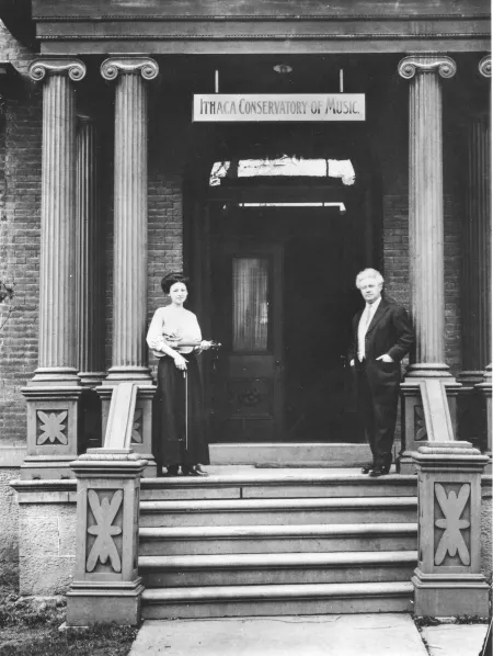 two people stand on the steps of the Ithaca Conservatory of Music building in this black and white historical photo