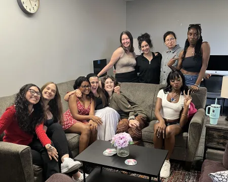 A group of 10 female college students sit around a couch for a group photo.
