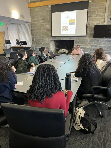 A group of college students in discussion around a table. 