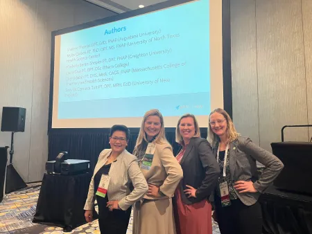 A group of physical therapists stand in front of a projection screen