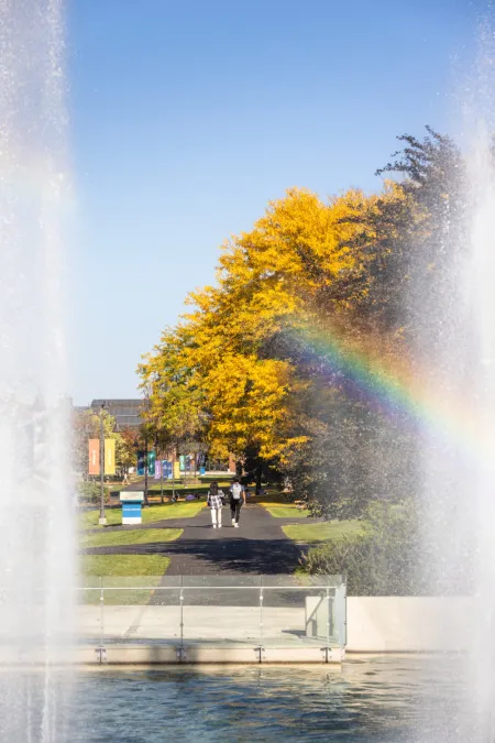 The academic quad as seen through the fountains with the water spray making a rainbow