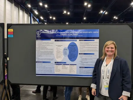 A PT professor stands in front of a poster