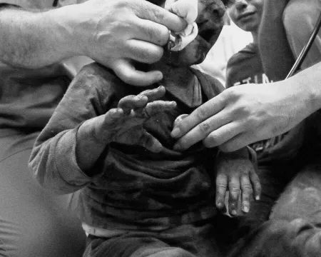 A small child is wiped clean by many hands.