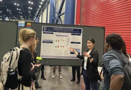 A PT professor and a group of PT students stand in front of a poster