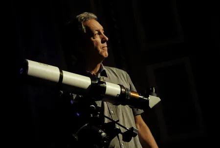 A man stands with a telescope. 