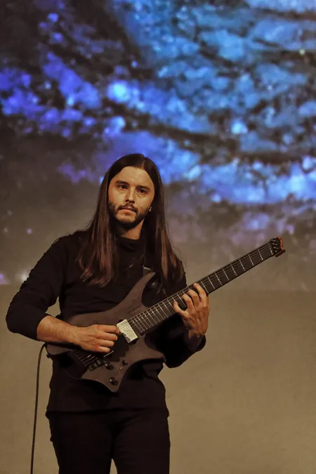 A man plays guitar onstage. 