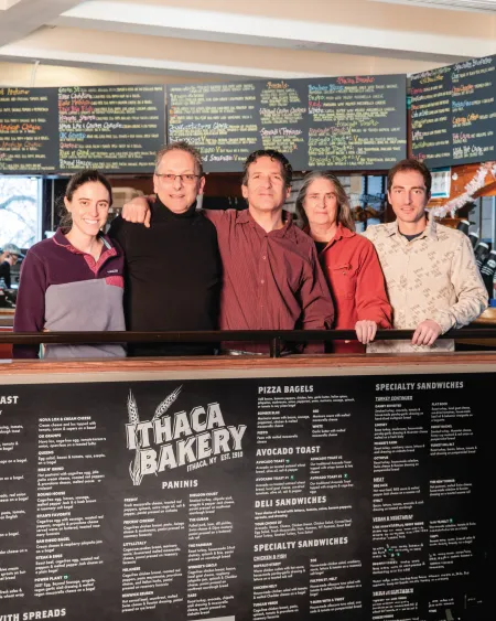 A family of two generations stands behind an Ithaca Bakery counter. 