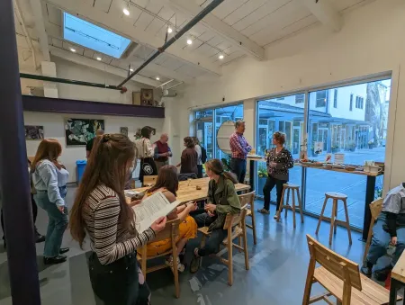 A group of students mingles in a large open interior space. 