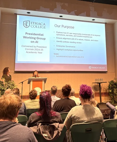 woman at podium with text on screen behind her while another woman stands by
