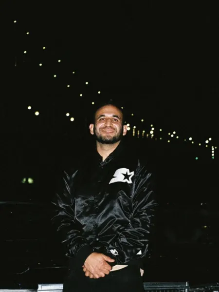 Headshot of Armando Lara-Millan. Armando is wearing a black Starter jacket.