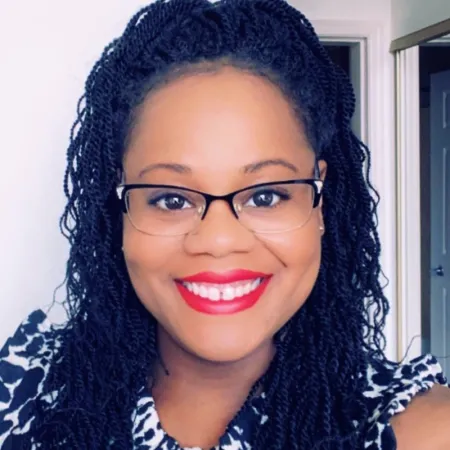 Headshot of Ashley Hall. Ashley is wearing a white and blue floral top and glasses.