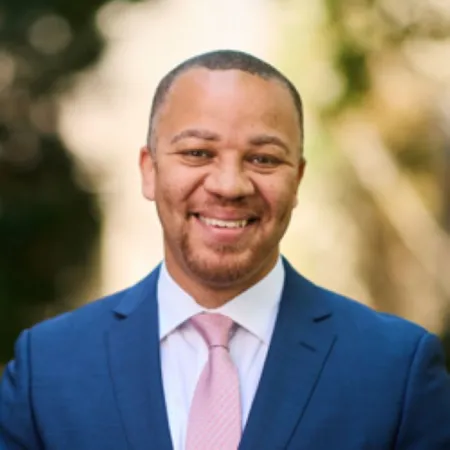 Headshot of Donathan L. Brown. Donathan is wearing a blue suit with a white dress shirt and pink tie.