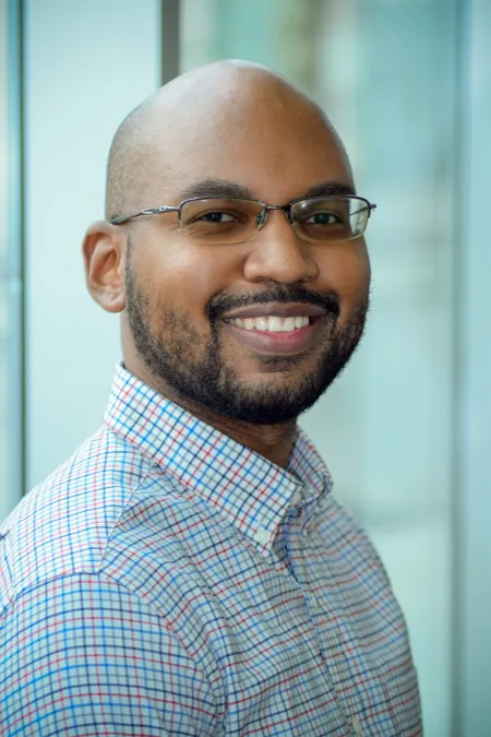 Jonathan Osborne Headshot. He is wearing a checkerboard patterned button down and glasses.