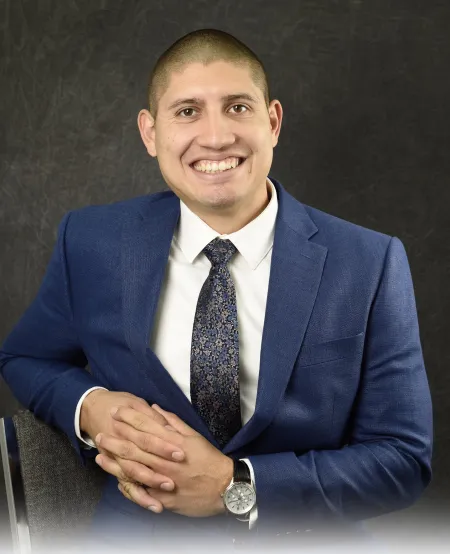 Headshot of Ryan Moruzzi. He is wearing a blue suit with a charcoal patterned tie and white dress shirt.