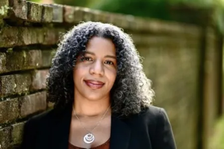 Headshot of Shauna M. Morgan. Shauna is wearing a black suit coat and is posed in front of brick wall.